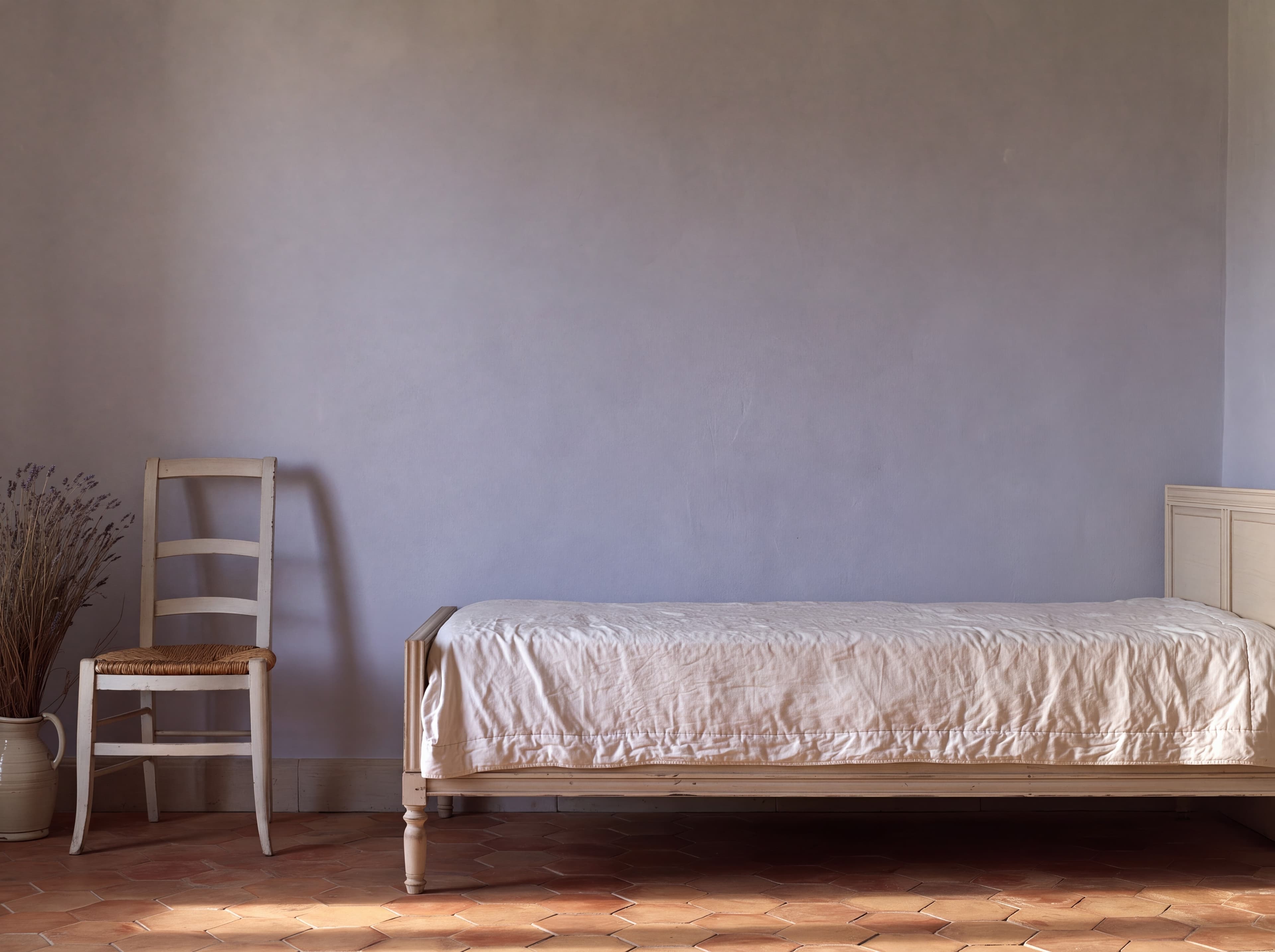 Provencal bedroom with a lavender gray lime wall, painted daybed with a white boutis quilt, rush chair, and dried lavender, ranked 16 among landscape poster mockups