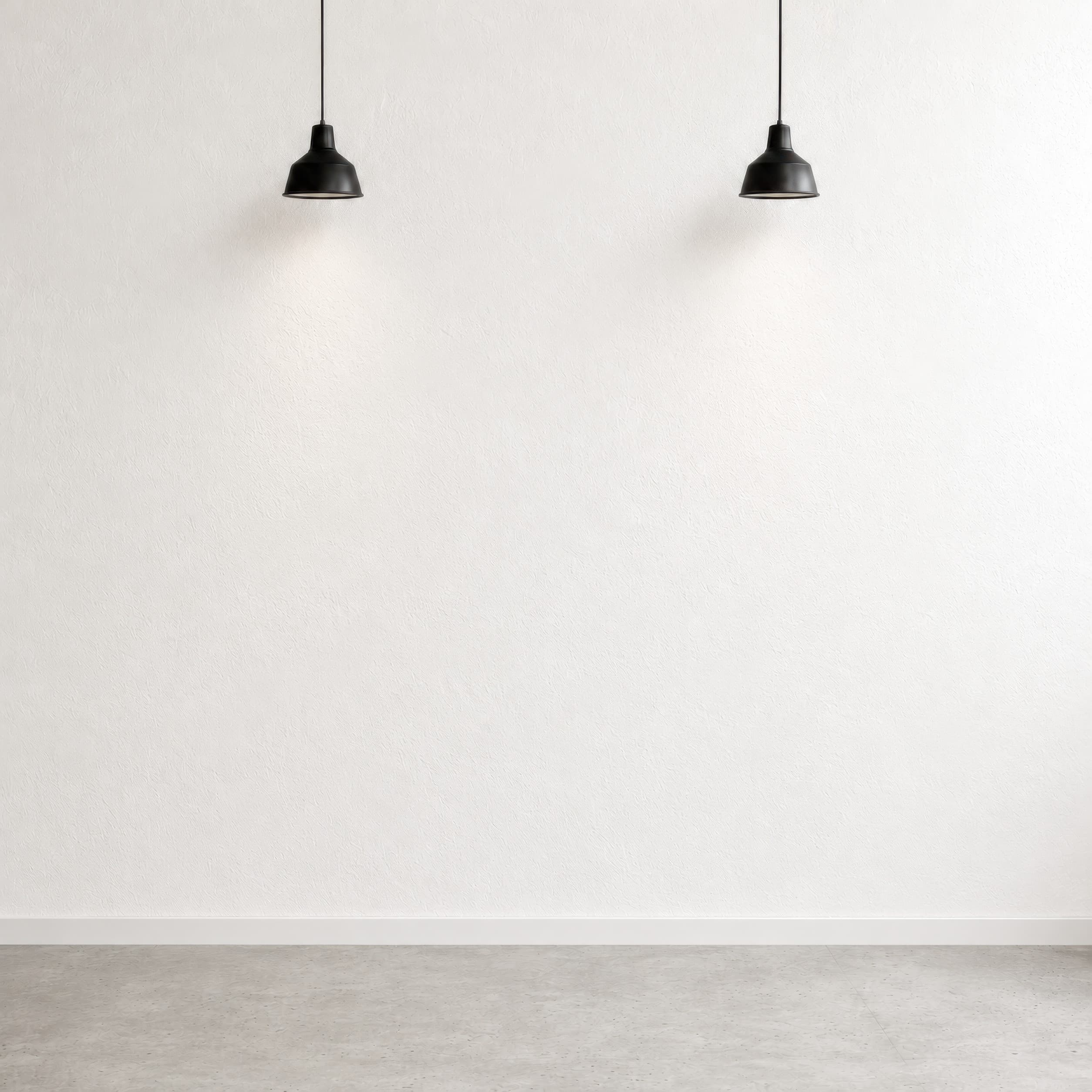 Minimal gallery-style interior with a bright empty white textured plaster wall, black pendant lights, and a pale gray floor, ranked 12 among exhibition mockups
