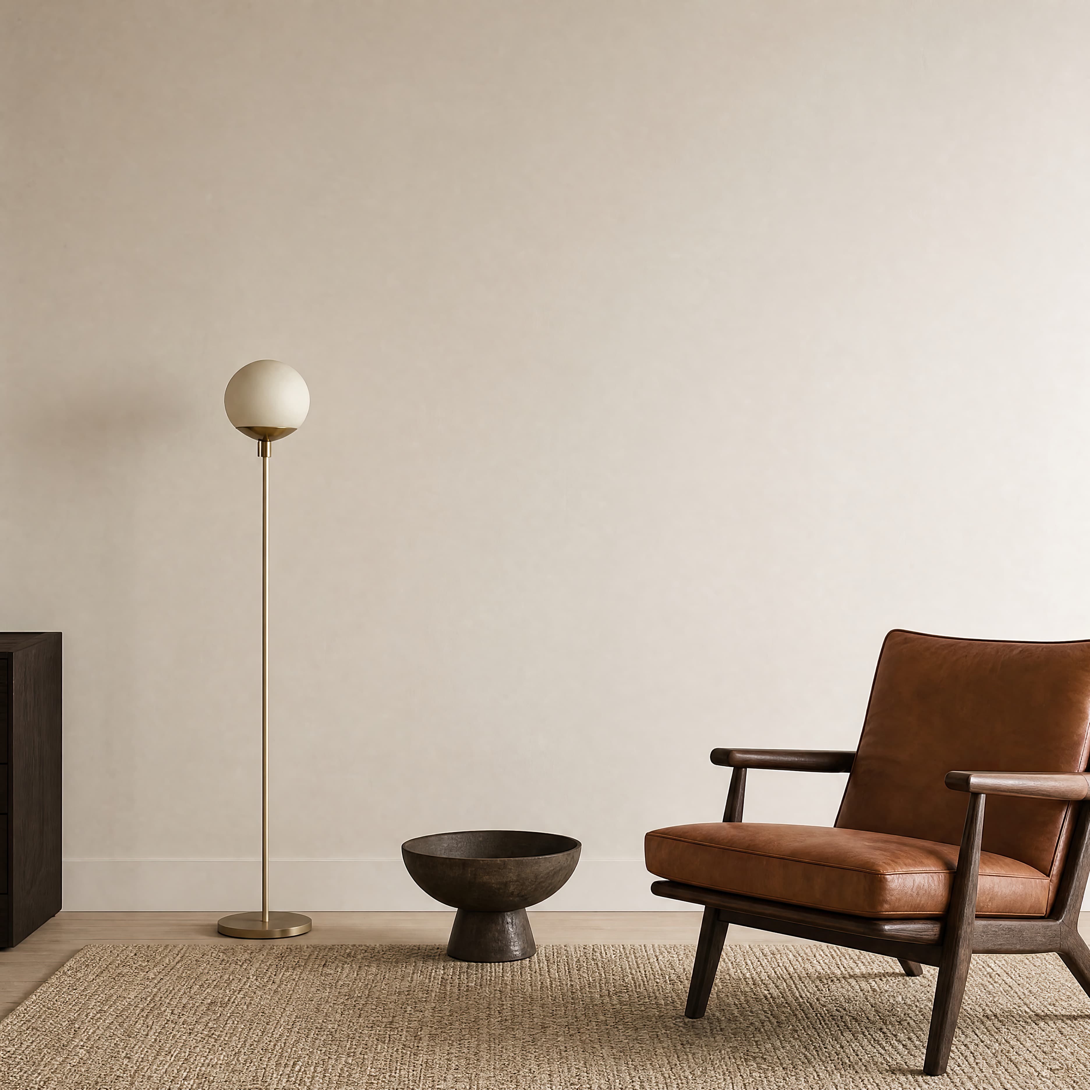 Minimal warm-ivory living room wall with a cognac leather chair and slender brass floor lamp, ranked 10 among triptych mockups