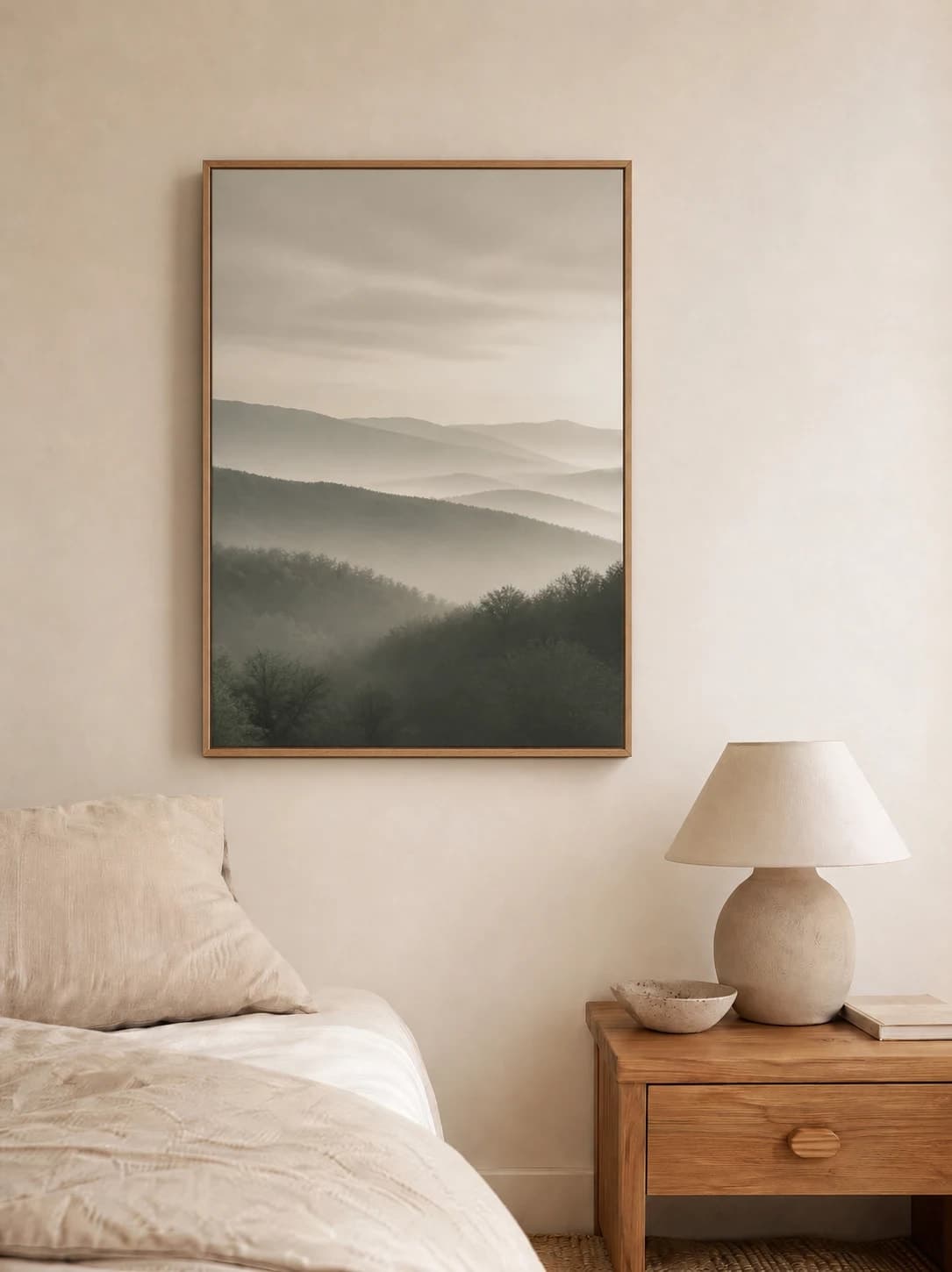 Foggy landscape print in a natural oak frame on a soft linen bedroom wall
