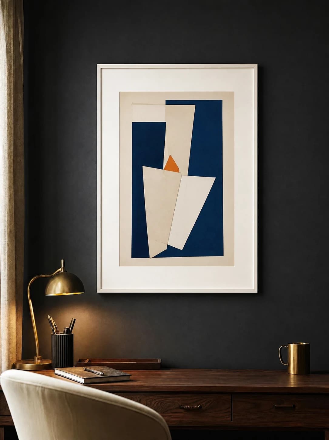 Cobalt geometric print in a white frame and mat above a walnut desk on a charcoal wall