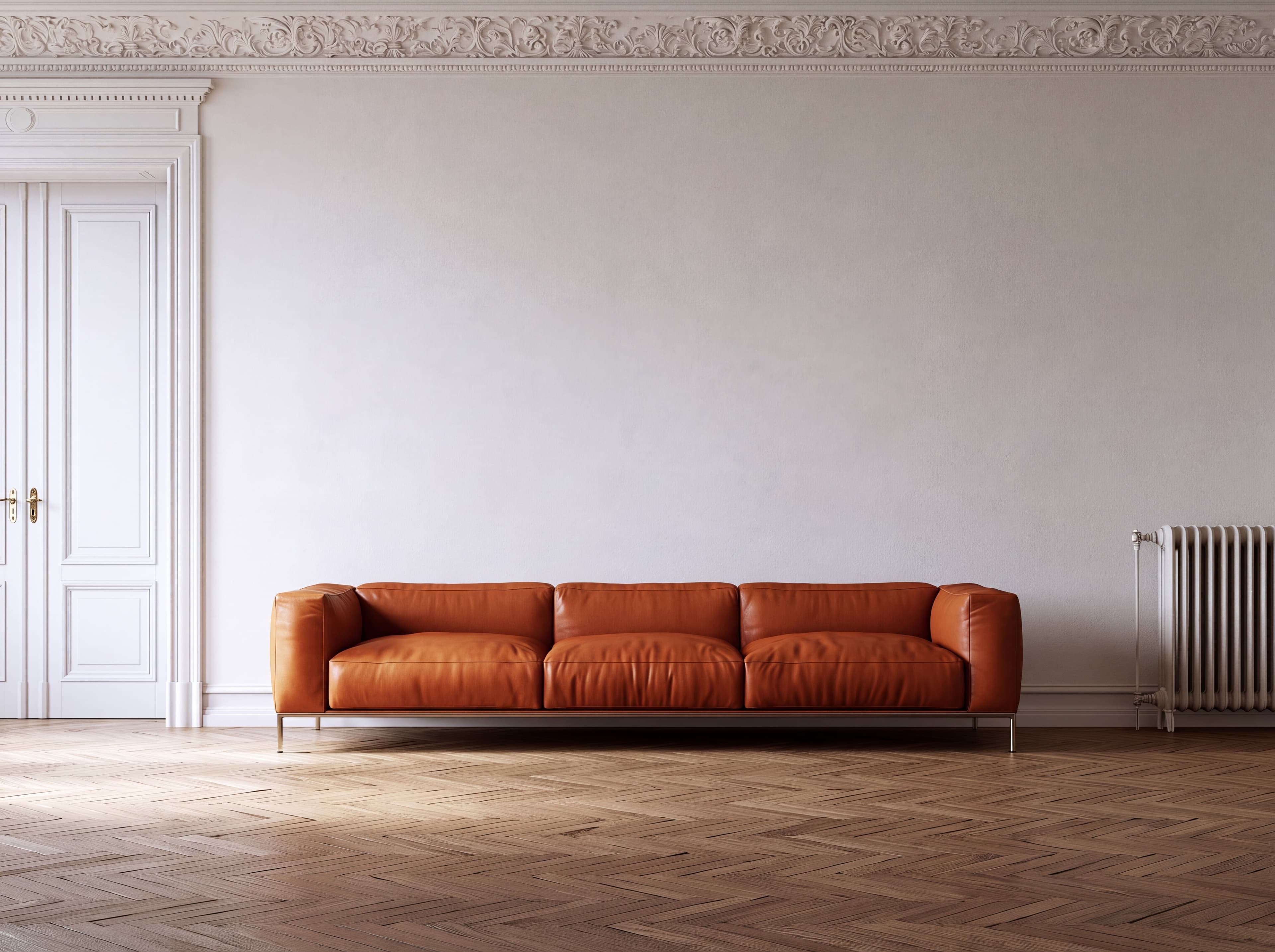 Berlin Altbau living room with a white plaster wall, ornate stucco cornice, cognac leather sofa, and oak herringbone parquet, ranked 1 among european room mockups