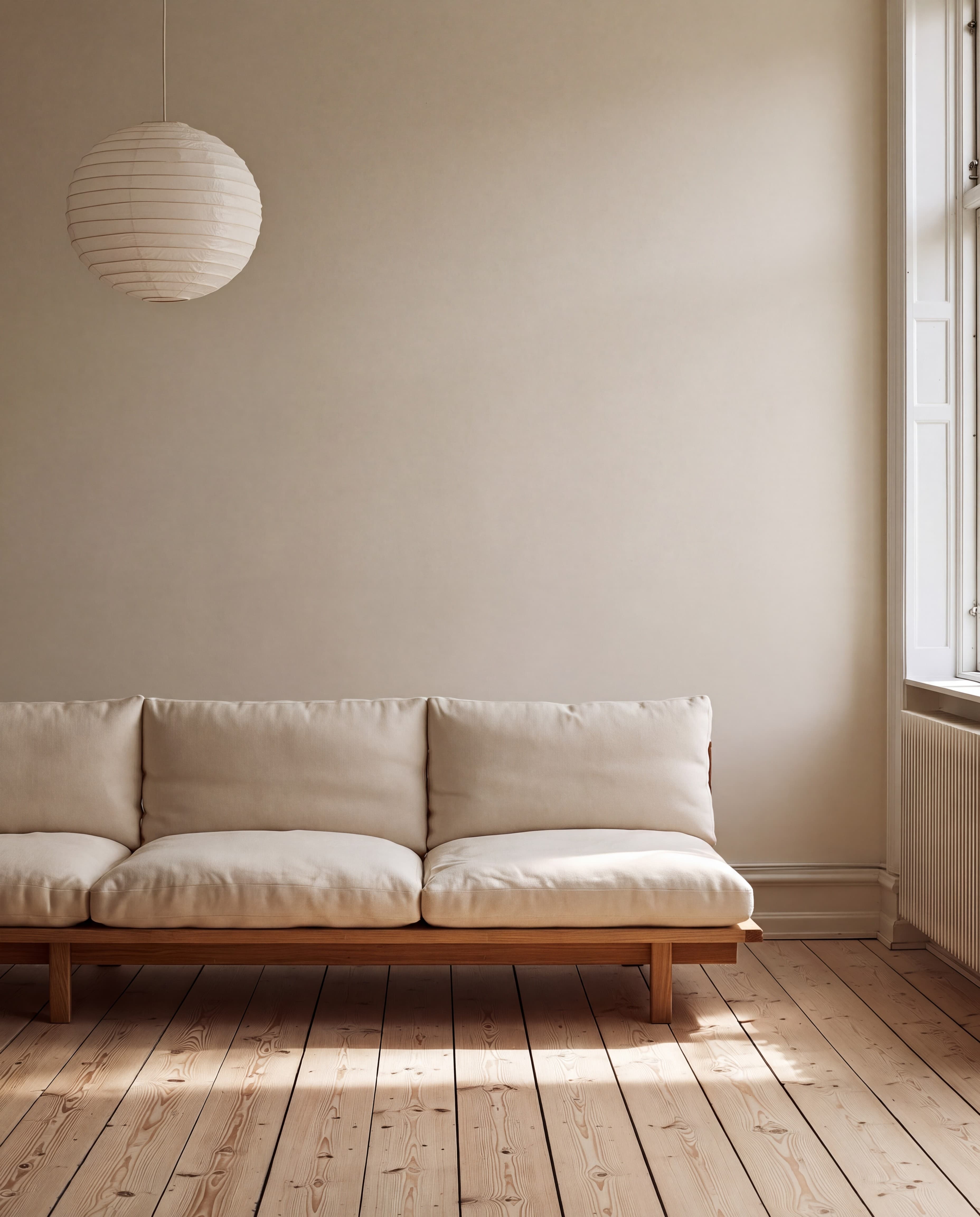Copenhagen apartment living room with a warm ivory wall, oak-frame daybed sofa, paper pendant lamp, and wide pine floorboards, ranked 2 among european room mockups