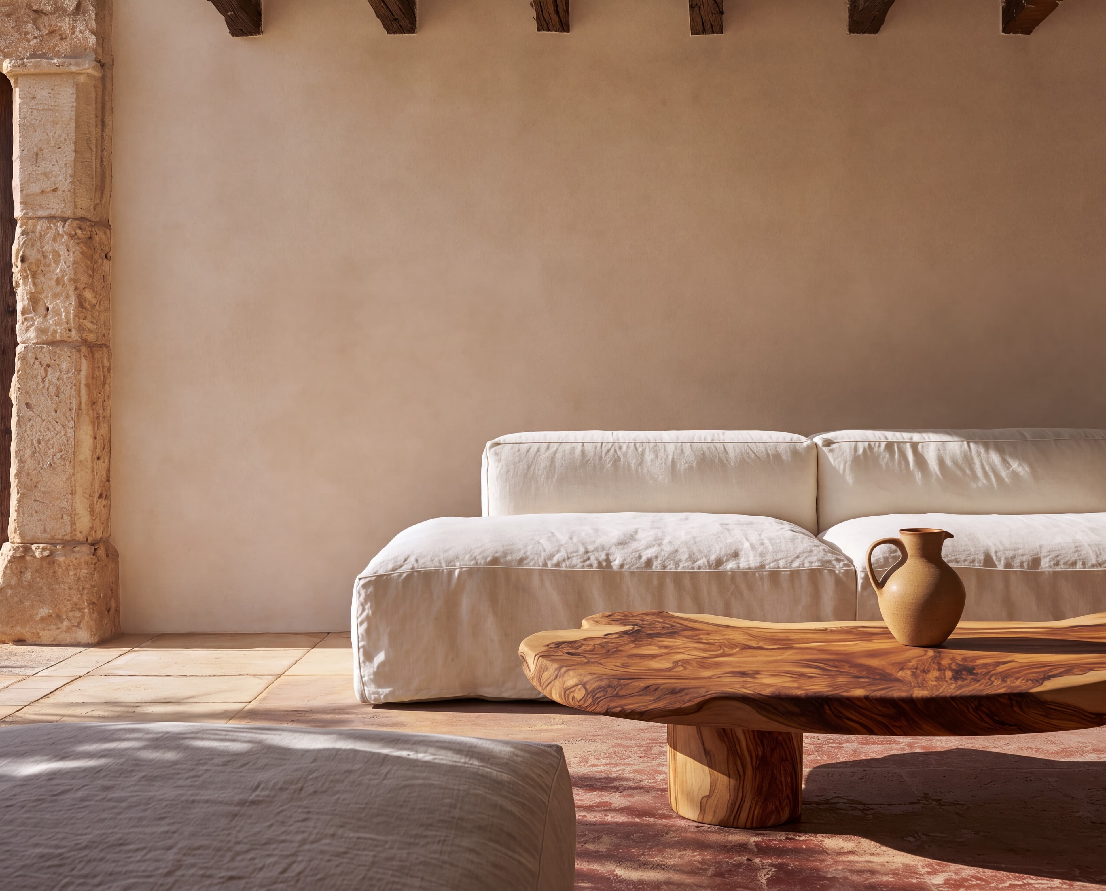 Mallorca finca living room with a sand limewash wall, wooden beams, white linen sofa, and olive-wood coffee table, ranked 16 among european room mockups