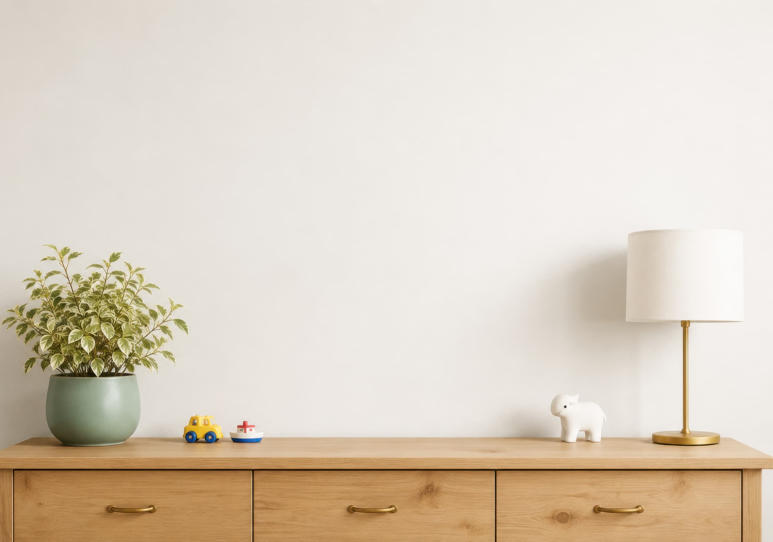 Bright children’s room wall mockup with a pale wood dresser, green plant, toy accents, white animal figurine, and brass table lamp., selected for nursery mockups