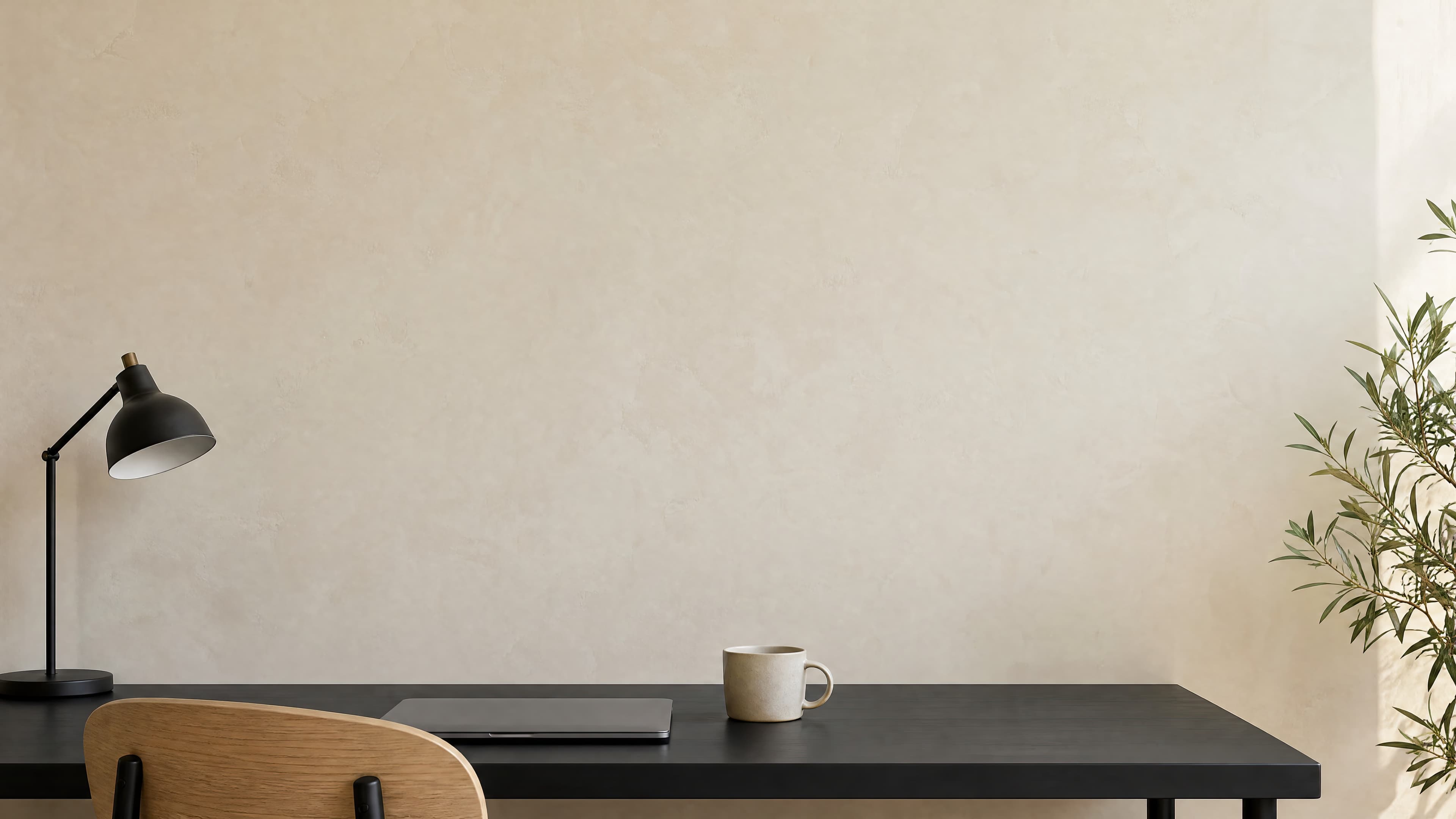 Minimal home office with a softly textured ivory limewash wall above a black desk and natural oak chair, ranked 12 among office mockups