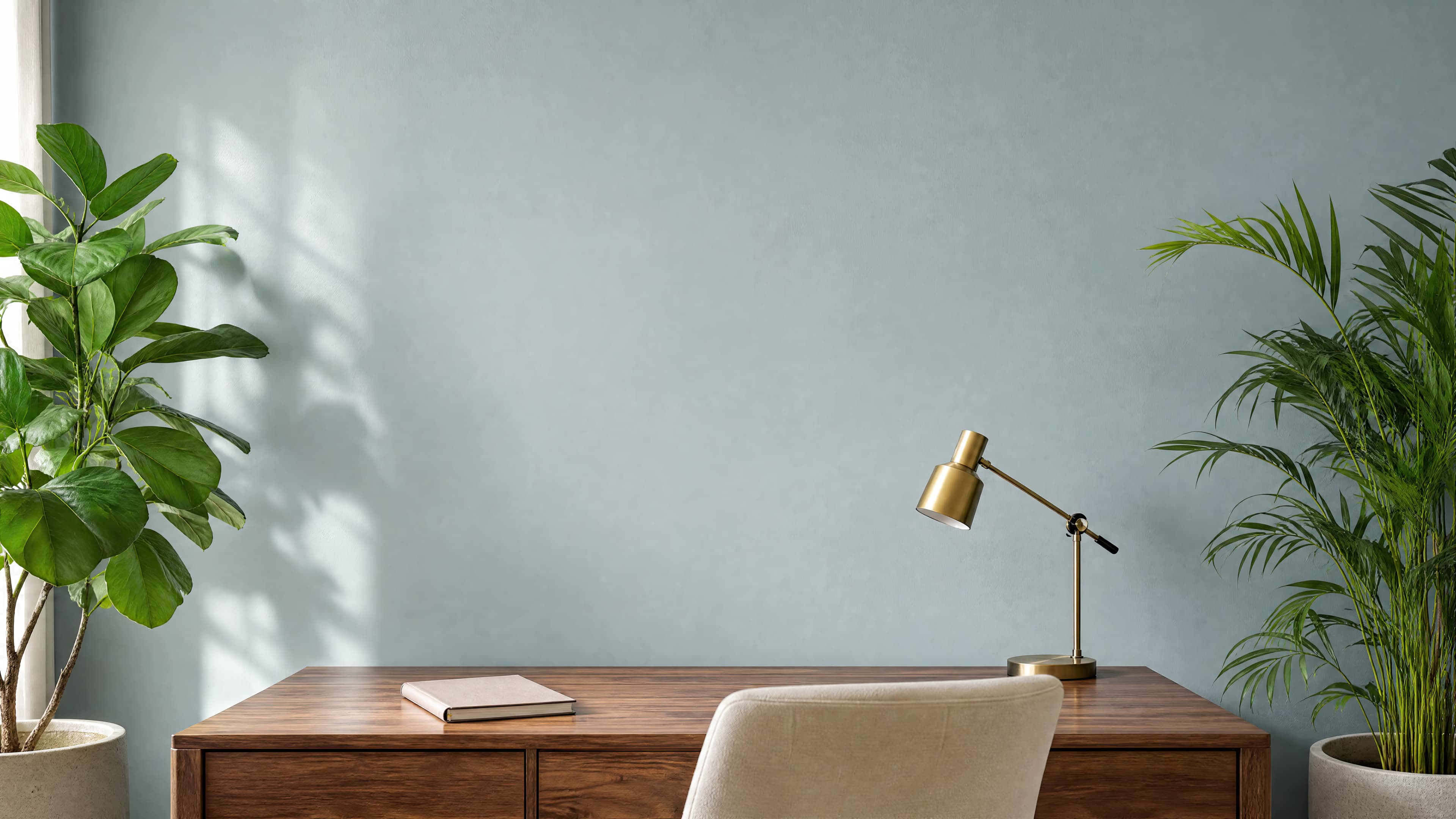 Bright contemporary office with an empty dusty-blue wall above a walnut desk framed by lush botanical plants, ranked 4 among office mockups