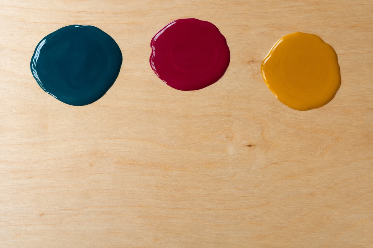 Close overhead process image of three glossy fluid-acrylic pools spread to twice their starting width before the panel is tilted
